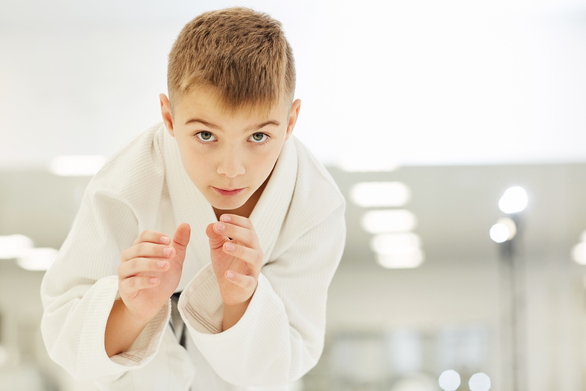 Portrait of young karateka in kimono standing and working with fighting techniques during training in karate